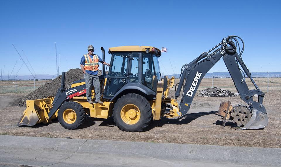 Scott Wightman standing on a backhoe on a freshly graded job site
